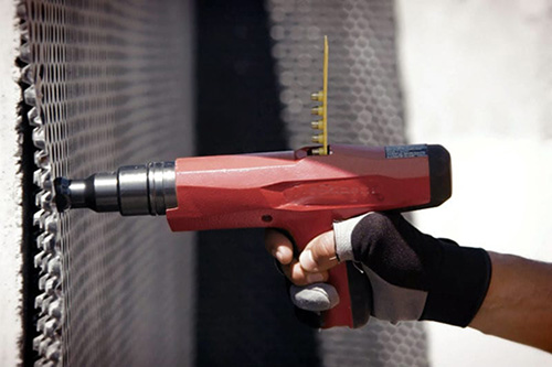 Powder actuated tool being used in construction